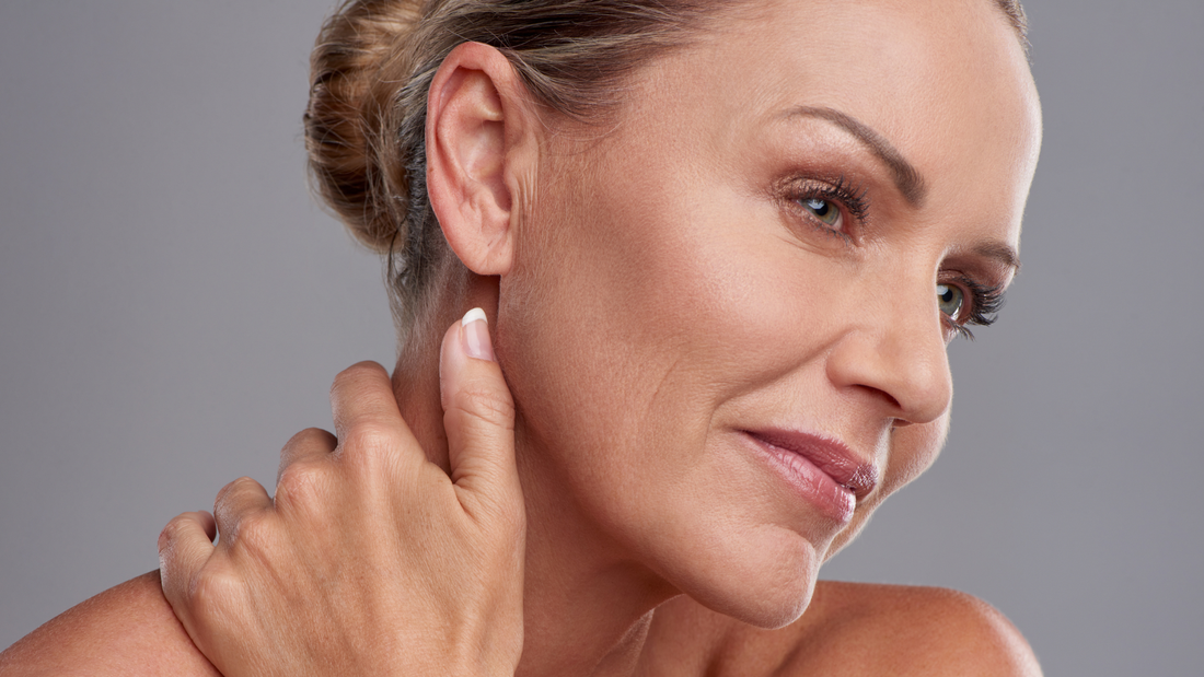 Femme aux mains sur le visage exprimant le besoin de confort et de soin pour une peau sèche qui tiraille.